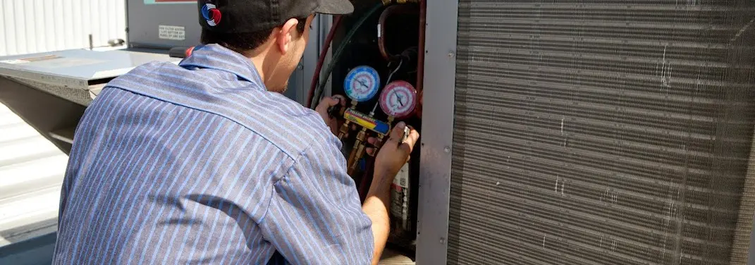 HVAC technician servicing a condenser unit in West Point