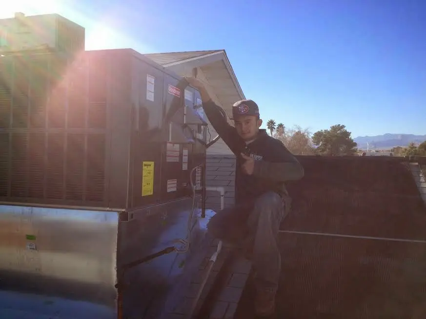 HVAC technician performing AC Tune-Up on a rooftop unit in West Point